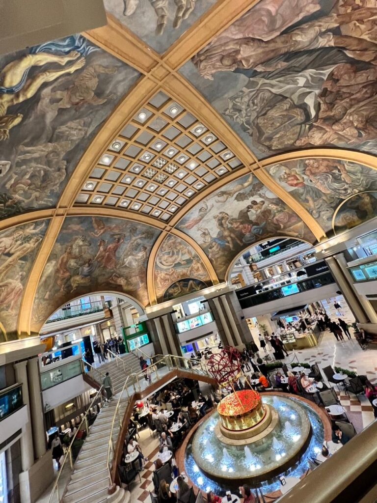 Interior das Galerías Pacífico em Buenos Aires, com sua cúpula decorada por murais e área central movimentada.